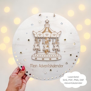 May include: A round, wooden advent calendar with a carousel design. The carousel features three reindeer and is surrounded by star cutouts. The text "Mein Adventskalender" is engraved on the wood. The image also includes the text "Laserdatei SVG, PDF, PNG, DXF Adventskalender".
