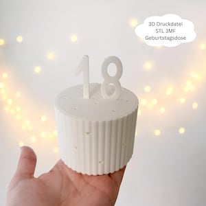 Puede incluir: Un recipiente blanco, cilíndrico, con forma de pastel y el número 18 en la parte superior. El recipiente tiene estrías verticales y pequeños recortes en forma de corazón. El texto en forma de nube dice "3D Druckdatei STL 3MF Geburtstagsdose."