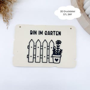 Könnte beinhalten: Cremefarbenes rechteckiges Schild mit den schwarzen Worten "BIN IM GARTEN". Eine schwarze Zaun- und Topfpflanzengrafik befindet sich unter dem Text. Das Schild hat zwei kleine Löcher zum Aufhängen. Der Text "3D Druckdatei STL 3MF" steht in einer Wolkenblase.