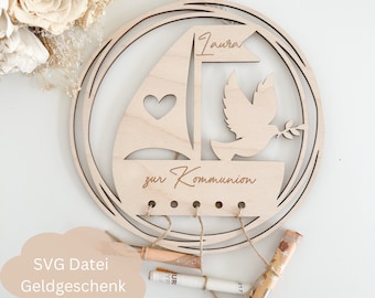 May include: A wooden sailboat with a dove and a heart cutout, with the text "Laura zur Kommunion" engraved on it. The sailboat is attached to a wooden ring with twine and has rolled up bills hanging from it.