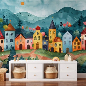 May include: A watercolor mural featuring a whimsical village with colorful houses, trees, and a rainbow. The mural is set against a backdrop of blue mountains and a bright yellow sun. A stuffed giraffe and whale are in the foreground.