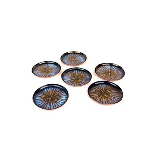May include: Six small, round coasters with a dark blue rim and a radial pattern in shades of gold and blue. The coasters are arranged on a white background, showcasing their decorative design. These coasters are ideal for protecting surfaces from drink rings.