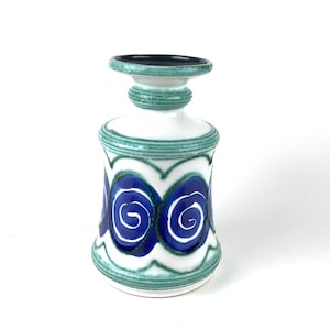 May include: A white ceramic vase with a blue and green design. The vase has a wide base and a narrow neck. The design features swirling blue lines on a white background.