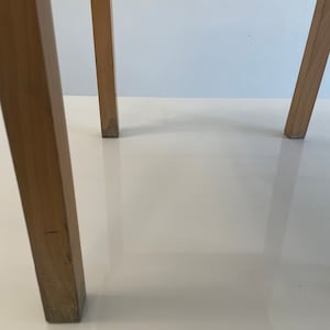 May include: Close-up of the wooden legs of a chair. The legs are a light brown color and have a smooth finish.