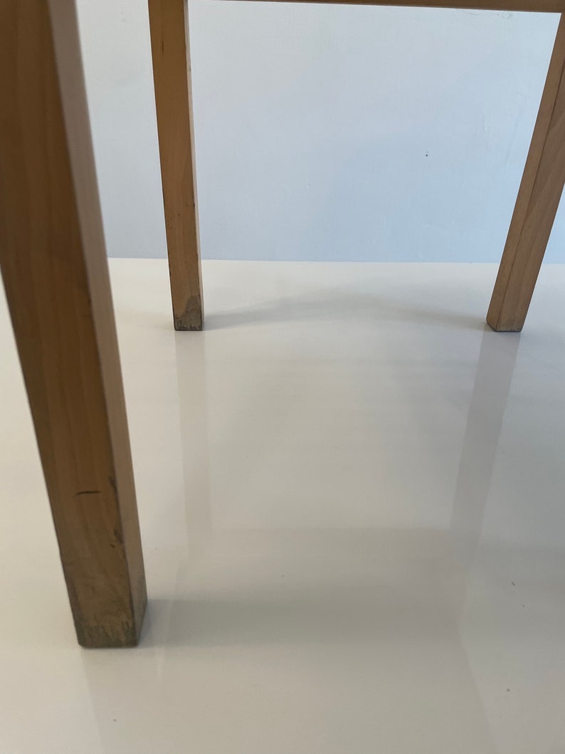 May include: Close-up of the wooden legs of a chair. The legs are a light brown color and have a smooth finish.
