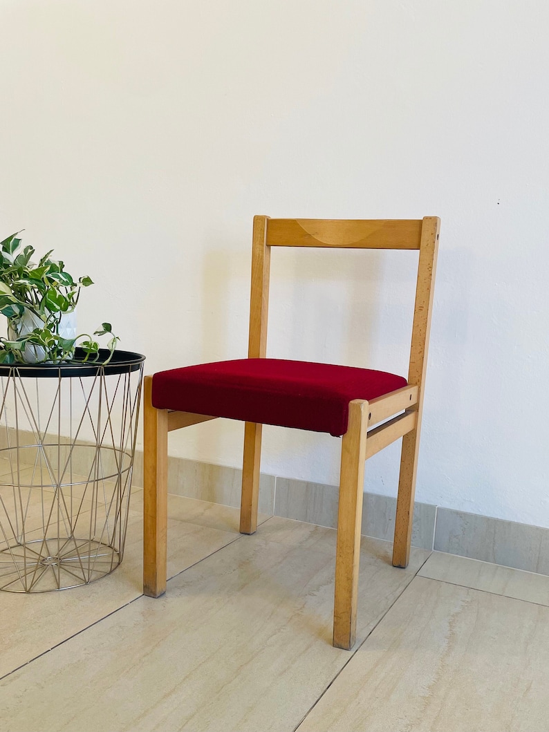 May include: A wooden chair with a red upholstered seat. The chair has a simple design with a straight back and four legs.