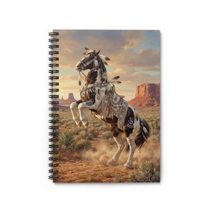 May include: Spiral-bound notebook featuring a painting of a rearing horse in a desert landscape. The horse is adorned with Native American-inspired designs and feathers. The background includes mesas and a sunset sky, evoking a sense of the American Southwest.