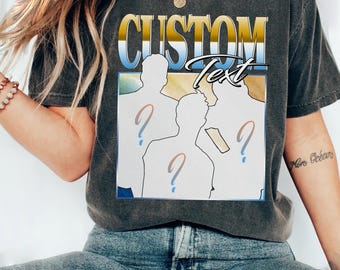 Może przedstawiać: Ciemnoszara koszulka z nadrukiem graficznym. Projekt zawiera słowo "CUSTOM" w kolorze złotym i niebieskim, z napisem "Text" poniżej. Sylwetki ludzi ze znakami zapytania również znajdują się w projekcie.