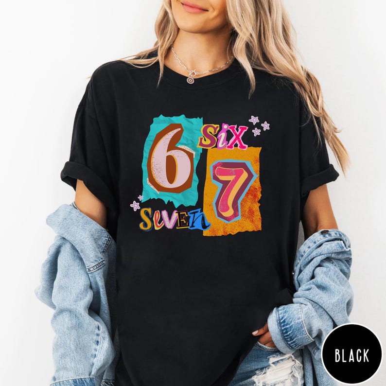May include: Black t-shirt with a colorful graphic design featuring the numbers "6" and "7" in a retro style. The word "Six" and "Seven" are also included in the design. The shirt is a casual, everyday wear item.
