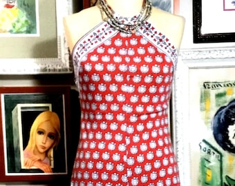 May include: A floor-length halter dress in a vibrant red hue, featuring a repeating pattern of small white and blue circular motifs. The garment has a fitted bodice with a high neckline and a long, straight skirt, displayed on a mannequin.