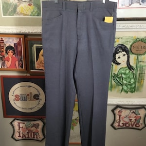 May include: A pair of gray straight-leg pants with a single back pocket. The pants are hanging on a clothing rack.