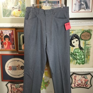 May include: Gray dress pants with a straight leg and a zipper fly. The pants have a tag attached to the right side.