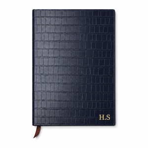 May include: A rectangular navy blue notebook with a textured crocodile skin pattern on the cover. The bottom right corner features the gold embossed initials H.S. A small brown ribbon bookmark extends from the bottom edge of the notebook.