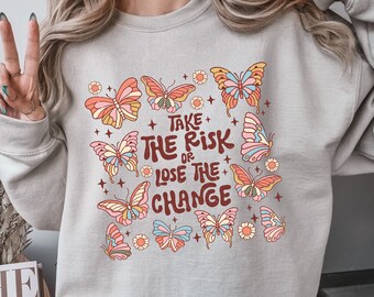 May include: A gray sweatshirt with a graphic print of butterflies and the text "Take the risk or lose the change".