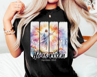 May include: Black t-shirt with a colorful image of Jesus Christ rising from the grave. The image is surrounded by a white border and the text "He is risen" and "Matthew 28:6" are printed below the image.
