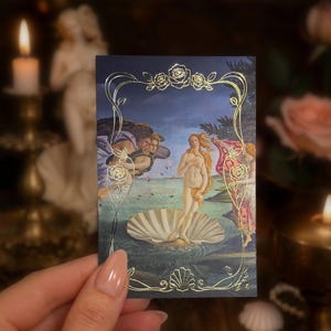 May include: A rectangular card featuring a reproduction of The Birth of Venus painting, framed by a gold foil border with rose and shell motifs. The artwork depicts a central figure standing in a large scallop shell on water, flanked by figures.