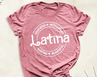 May include: A pink t-shirt with a white circle graphic that says "Latina" with the words "Educated", "Intelligent", "Strong", and "Beautiful" around the circle.