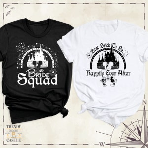Peut inclure: Deux t-shirts noir et blanc avec un motif de ch&acirc;teau Disney et du texte. Le t-shirt noir dit "Bride Squad" et le t-shirt blanc dit "Best Bride To Be Happily Ever After".