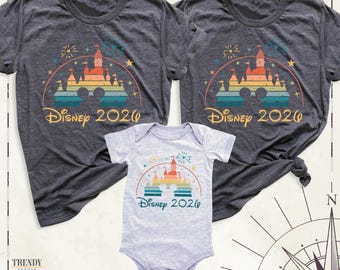 May include: Two dark heather gray short-sleeve t-shirts and one light gray short-sleeve baby bodysuit. Each garment features a colorful graphic of a castle silhouette with a Mickey Mouse head outline, fireworks, and the text Disney 2026.