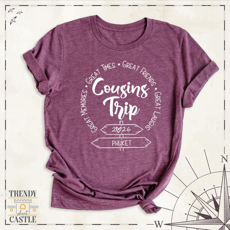 Peut inclure: Un t-shirt &agrave; manches courtes bordeaux chin&eacute; avec un texte blanc indiquant Cousins Trip, 2026 et Phuket, entour&eacute; des phrases Great Times, Great Friends, Great Laughs et Great Memories dispos&eacute;es dans un motif circulaire.