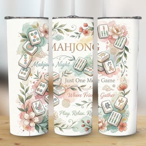 May include: A white tumbler with a watercolor design featuring Mahjong tiles, flowers, and the text "MAHJONG". The design includes the phrases "Mahjong Night", "Just One More Game", and "Where Friends Gather".