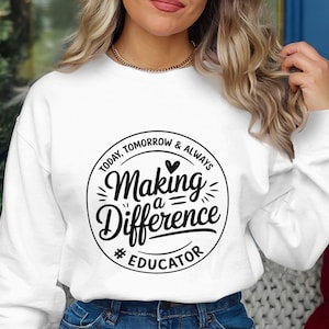 Może przedstawiać: Biała bluza z czarną okrągłą grafiką z napisem "Today, Tomorrow & Always Making a Difference #Educator". Bluza jest połączona z niebieskimi dżinsami.