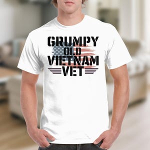 May include: White t-shirt with a black graphic that says "Grumpy Old Vietnam Vet" with an American flag design.
