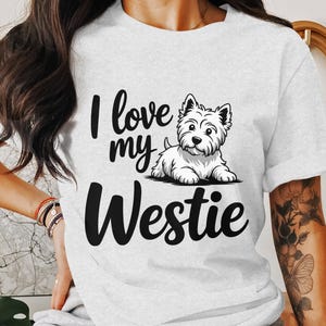 Könnte beinhalten: Weißes T-Shirt mit einer schwarzen Grafik, auf der "I love my Westie" steht, und einem Cartoon-Bild eines weißen Westie-Hundes.