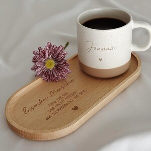 Keramiktasse mit personalisierter Namensgravur, befüllt mit Kaffee – auf Tablett serviert. Beige Tasse mit matter Oberfläche und 360 ml Volumen, perfekt für den Start in den Tag. Geschenk für Kolleg:innen, Freund:innen oder Familie, ideal für Abschied oder als kleine Überraschung. Zeitloses Design, langlebig, spülmaschinengeeignet, liebevoll graviert und dekorativ. Steingut Tasse. Personalisierte Geschenke