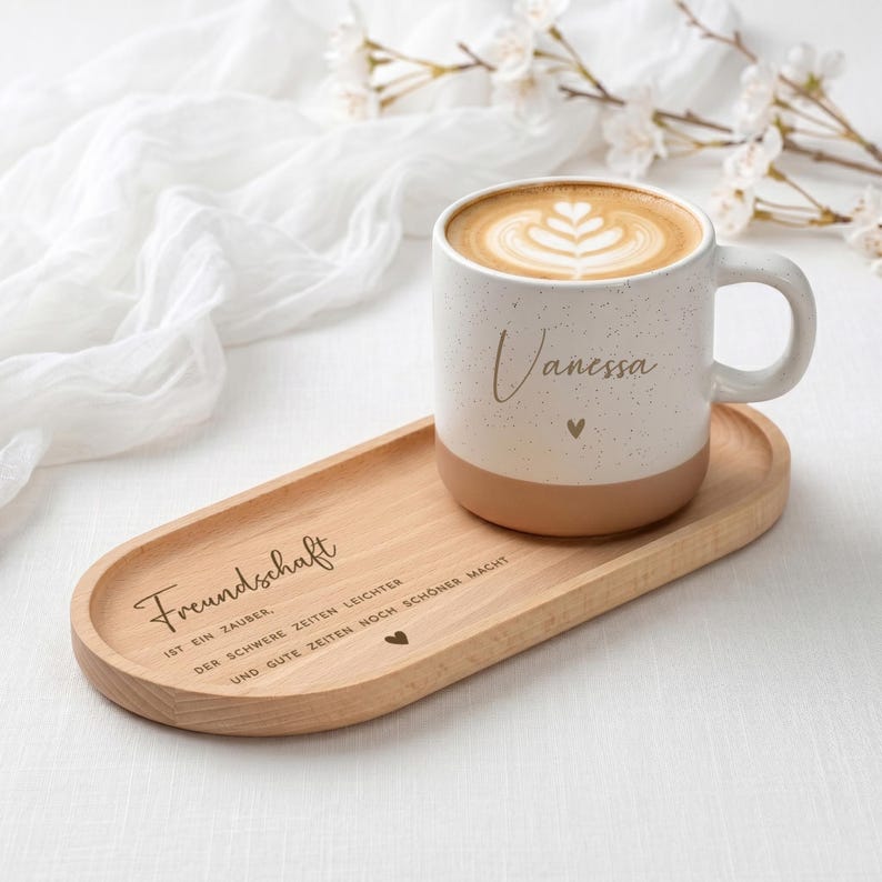 Keramiktasse mit personalisierter Namensgravur, befüllt mit Kaffee – auf Tablett serviert. Beige Tasse mit matter Oberfläche und 360 ml Volumen, perfekt für den Start in den Tag. Geschenk für Kolleg:innen, Freund:innen oder Familie, ideal für Abschied oder als kleine Überraschung. Zeitloses Design, langlebig, spülmaschinengeeignet, liebevoll graviert und dekorativ. Steingut Tasse. Personalisierte Geschenke