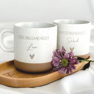 Detailaufnahme der personalisierten Tasse mit individueller Namensgravur. Weiße Keramiktasse mit gesprenkeltem Muster, matter Oberfläche und unglasiertem Boden. Perfekt als Geschenk für Freundin, Kollegin oder als kleine Aufmerksamkeit für besondere Menschen – geeignet für Kaffee, Tee oder heiße Schokolade. Mikrowellen- und spülmaschinenfest. Stilvoll und liebevoll gestaltet.Steingut Tasse . Geschenk für Herzensmensch und Lieblingsmensch