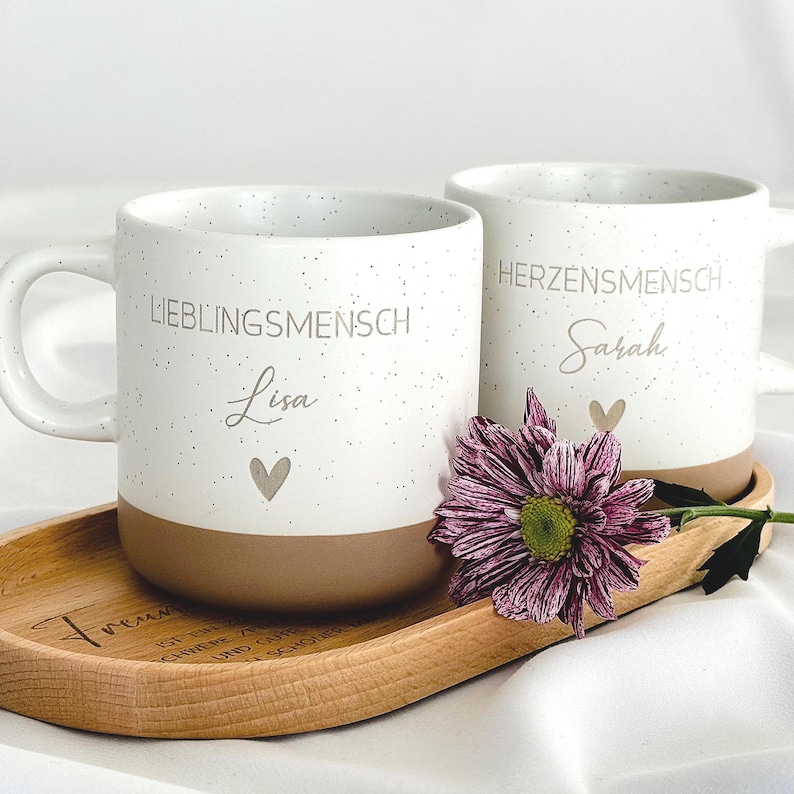 Detailaufnahme der personalisierten Tasse mit individueller Namensgravur. Weiße Keramiktasse mit gesprenkeltem Muster, matter Oberfläche und unglasiertem Boden. Perfekt als Geschenk für Freundin, Kollegin oder als kleine Aufmerksamkeit für besondere Menschen – geeignet für Kaffee, Tee oder heiße Schokolade. Mikrowellen- und spülmaschinenfest. Stilvoll und liebevoll gestaltet.Steingut Tasse . Geschenk für Herzensmensch und Lieblingsmensch