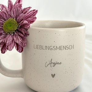 Nahaufnahme einer personalisierten Keramiktasse mit Namensgravur. Elegantes mattes Beige, feine Sprenkel, 360 ml. Ideal für Kaffee, Tee oder heiße Schokolade. Individuelles Geschenk für Freundin, Familie oder Kollegin.