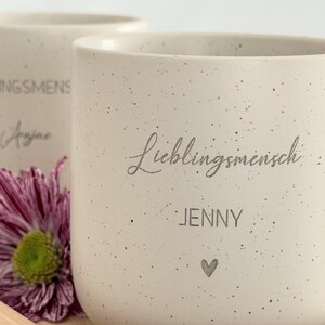 Obenansicht eines personalisierten Tassen-Sets: beige Keramiktasse mit Name auf graviertem Holztablett. Modernes, minimalistisches Design, perfekt als Geschenkidee für besondere Menschen.