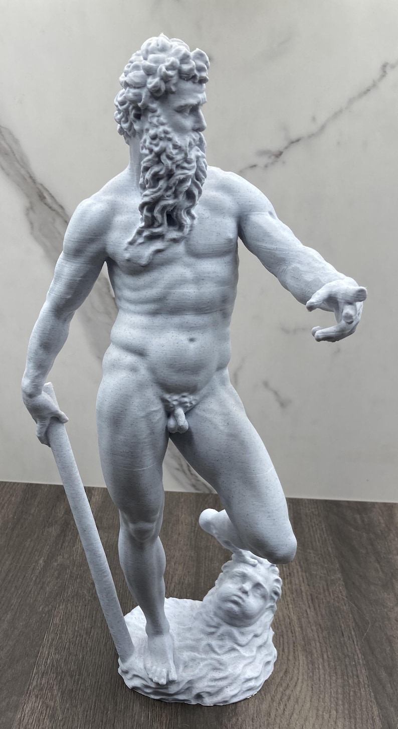 Puede incluir: Estatua gris de una figura masculina musculosa con barba larga, sosteniendo un bast&oacute;n. La estatua est&aacute; sobre una base esculpida con una cara. La figura desnuda tiene una superficie detallada y texturizada.