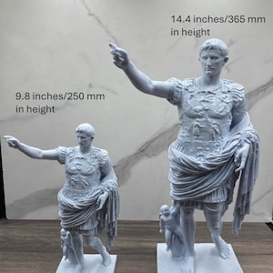Puede incluir: Comparaci&oacute;n de tama&ntilde;o de dos estatuas grises de un emperador romano. Una estatua mide 250 mm de altura, la otra 365 mm. Las estatuas est&aacute;n sobre bases cuadradas y presentan detalles de vestimenta. El texto "Size Comparison" est&aacute; arriba.