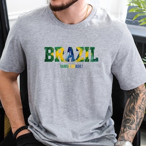 以下が含まれることがあります： 黒い持ち手と「But First, Coffee」のテキストが黒い太字で書かれた白いセラミックマグ。マグカップはぼやけた背景に置かれており、居心地の良い環境を示唆しています。