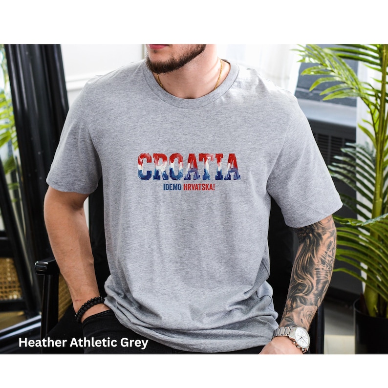 K&ouml;nnte beinhalten: Graues T-Shirt mit dem Wort "CROATIA" in Rot, Wei&szlig; und Blau, darunter der Text "IDEMO HRVATSKA!". Das T-Shirt hat einen Rundhalsausschnitt.