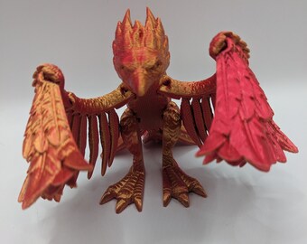 May include: A 3D printed figurine of a mythical creature with red and gold wings, a red head, and gold talons. The creature is standing on a white surface.