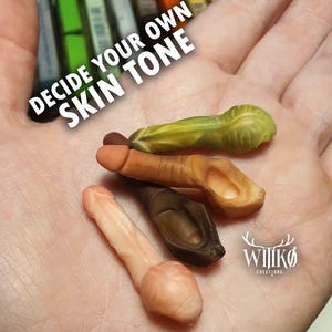 Puede incluir: Una mano que sostiene varios objetos pequeños esculpidos en varios tonos de piel. Se muestra el texto "DECIDE YOUR OWN SKIN TONE". Los objetos son en tonos de rosa, marrón y verde. El logotipo "WIIKØ CREATIONS" es visible.