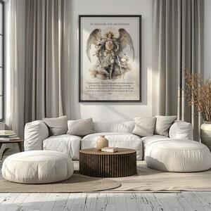 May include: A framed print of St. Michael the Archangel hangs above a white sectional sofa. The artwork depicts the archangel with wings, holding a sword. The room features neutral tones, a wooden coffee table, and two round ottomans.