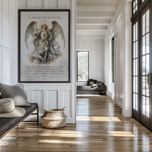 May include: A framed print of St. Michael the Archangel hangs on a white wall. The artwork depicts the archangel with wings, holding a sword. The print includes text at the bottom. A bench with pillows and a hat sits below the print.