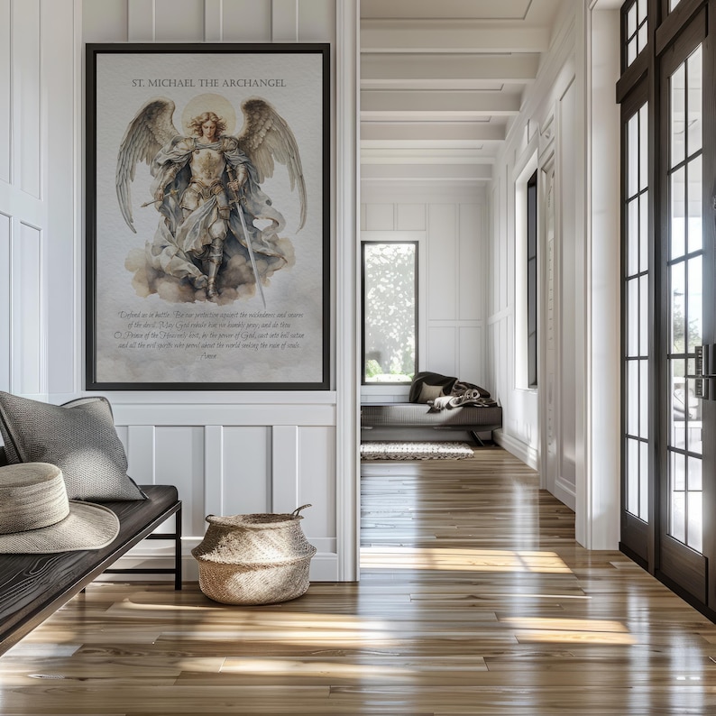 May include: A framed print of St. Michael the Archangel hangs on a white wall. The artwork depicts the archangel with wings, holding a sword. The print includes text at the bottom. A bench with pillows and a hat sits below the print.