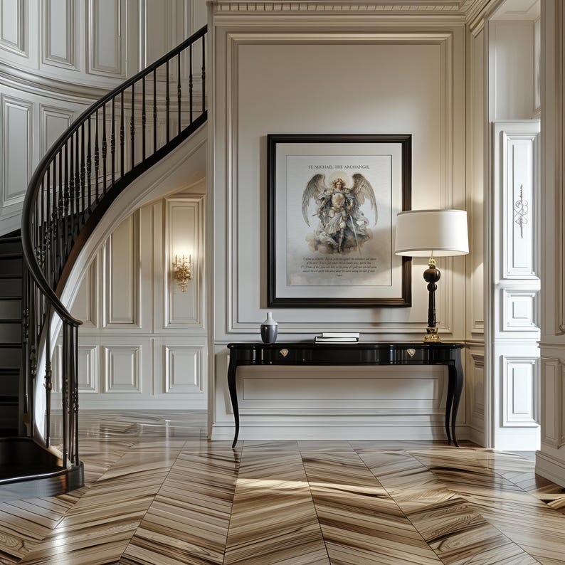 May include: An elegant entryway with a curved staircase and a black console table. A framed artwork of an angel hangs above the table, next to a lamp with a white shade. The floor has a patterned wood design.
