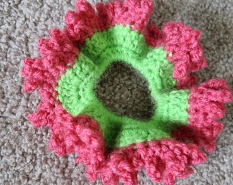 May include: A green and pink crocheted hair scrunchie with a ruffled edge.