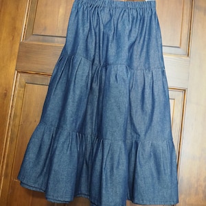 May include: A dark blue denim skirt with multiple tiers. The skirt has a wide elastic waistband.