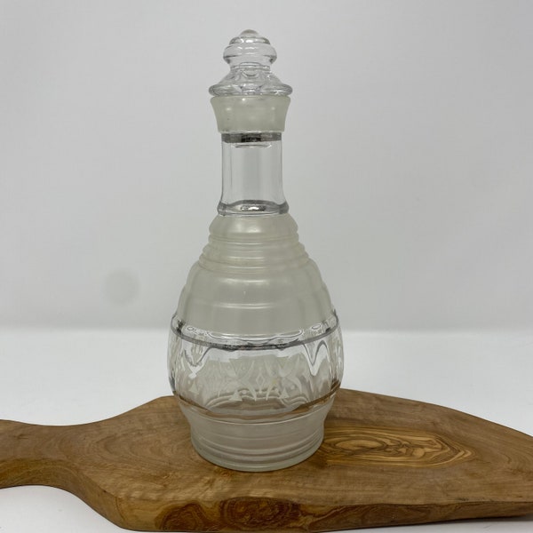 Hazel Atlas 1940s decanter with original stopper. Preowned w/o cracks or chips. Frosted and clear glass. Silver accent strips around bottle