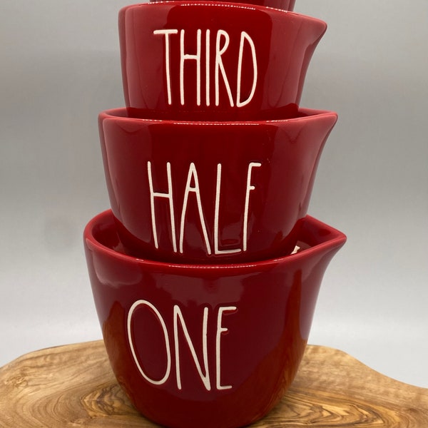 Ceramic set of red measuring cups by Rae Dunn Magenta. Each cup has the measurements spelled out and a cut out heart on the other. New