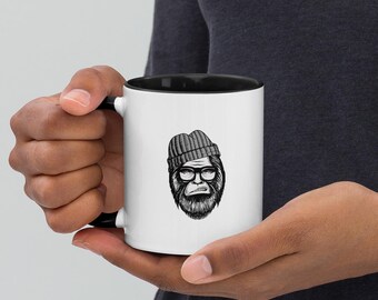 May include: A white ceramic mug with a black rim and handle. The mug features a black and white illustration of a creature wearing a beanie and glasses.