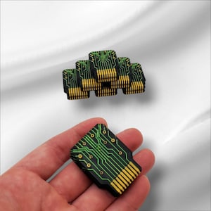 May include: A stack of black and green circuit board-style memory cards. A single card is held in a hand, showing the green circuit board design.